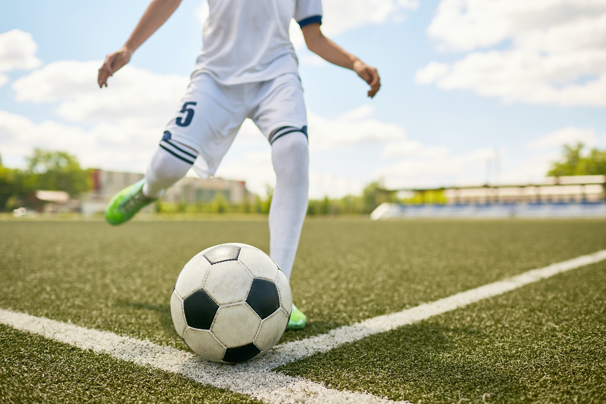 boy-kicking-ball-on-football-field